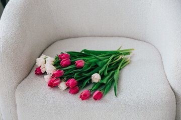 Freshly cut tulips arranged gracefully on a soft upholstered chair in a bright indoor setting