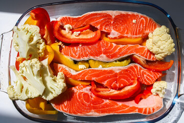 Salmon fillets with vibrant vegetables ready for baking in a glass dish