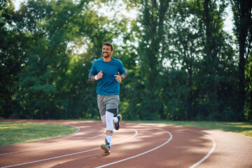 Happy athlete running on track while exercising outdoors.