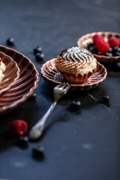 Still life with berries and sweet cupcake on porcelain plate with powdered sugar close up