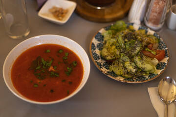 a plate of red borscht with herbs and salad
