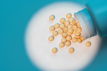 Close up of yellow medical pills on white background with blue shadows