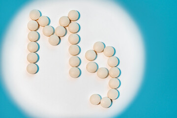 Magnesium, Mg symbol made from pills on white background with blue shadows. Healthcare concept