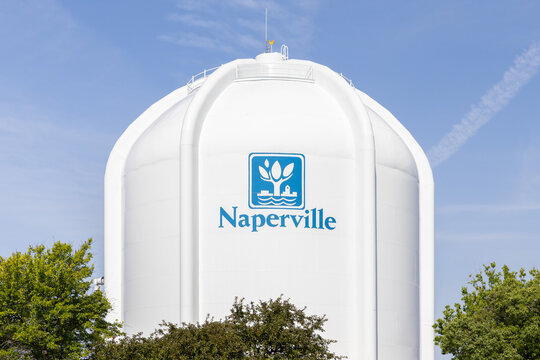 Naperville, IL, USA - July 2, 2025: A white water tower in Naperville with the city logo on it and a blue sky in the background.