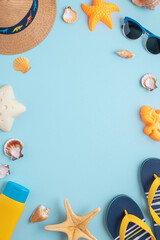 Colorful and playful summer frame from kids beach molds, straw hat, sandals and sunglasses on blue background. Top view. Copy space