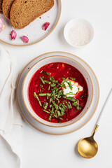 Traditional Ukrainian borscht with sour cream, garlic and rye bread on white table. Top view