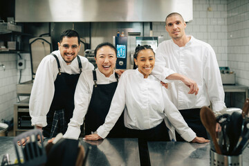 Portrait of smiling male and female chefs standing with each other in kitchen at restaurant