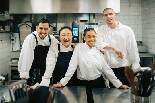 Portrait of smiling male and female chefs standing with each other in kitchen at restaurant