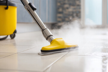 Steam cleaning tile floors in a modern kitchen during daylight hours for deep sanitization and shine
