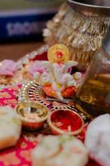 Ganesha Idol on Decorated Tray: A small Ganesha idol rests on a tray adorned with flowers and small...
