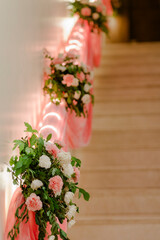 Staircase floral arrangements: pink and white flowers, greenery, and soft pink fabric decorate the staircase railing, creating a romantic and festive atmosphere.