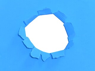 Torn hole on blue paper on smooth white background. Sheet of blue torn paper with blank space for...