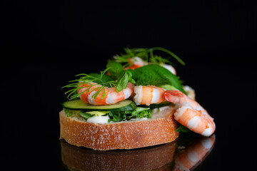 appetizing sandwich with salad and shrimps on a black background