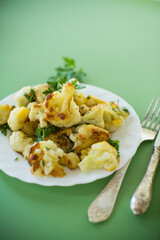 Fried cauliflower with spices and herbs on a green background