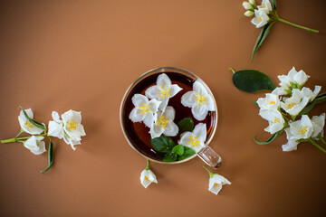 Brewed green tea with jasmine flowers on a brown background