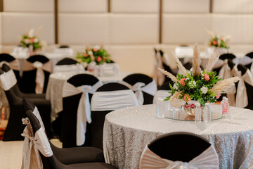 Elegant wedding reception setup with floral centerpieces and beautifully decorated chairs. Perfect for a celebration.