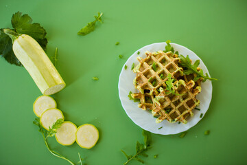 Vegetable zucchini waffles with greens on a green background