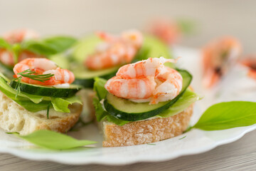 Appetizing appetizers with shrimps, sauce and cucumbers on a wooden table