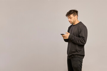 Side view of a Latino man texting on smartphone with ample copy space