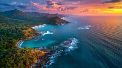 Aerial view of shoreline with glassy ocean surface glowing under dramatic golden sunset