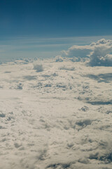 Vast clouds stretch across the horizon under a serene blue sky captured during a daytime flight