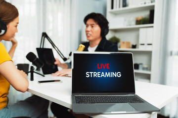 Selective focusing on live streaming laptop screen on blurry background of smiling radio influencer...
