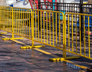 Yellow metal barrier on the edge of the concrete paved walkway.