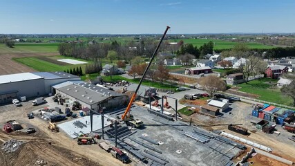 Drone footage of a construction site with a crane lifting steel beams in a rural area with green fields and scattered houses captivating scenes stunning visuals vibrant colors smooth motion
