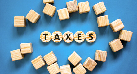 Taxes symbol. Concept word Taxes on beautiful wooden circles. Beautiful blue table blue background....