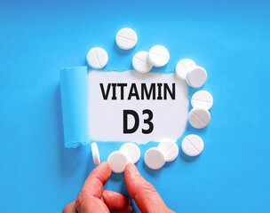 Vitamin D3 symbol. Concept words Vitamin D3 on beautiful white paper. White pills tablets. Doctor's hand. Beautiful blue background. Medical healthy lifestyle Vitamin D3 concept.