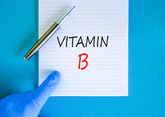 Vitamin B symbol. Concept words Vitamin B on beautiful white note. Doctor's hand in blue medical glove. Black pen. Beautiful blue background. Medical healthy lifestyle Vitamin B concept.