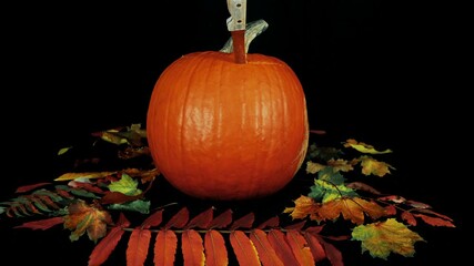 A disembodied knife carving a Halloween pumpkin into a Jack o' Lantern. Shot in stop motion, time lapse.