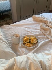 Avocado and eggs toast on bed with coffee