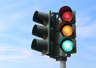 Traffic light with all lights on with the sky as background