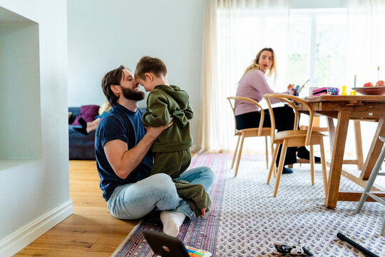 Father spending leisure time playing with son while sitting on floor at home