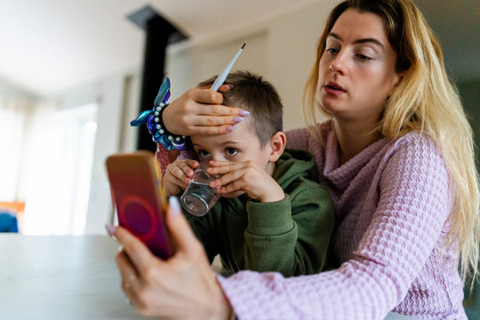 Mother discussing son's high fever with doctor during telemedicine appointment