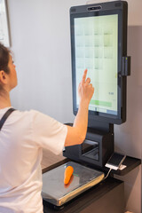 Woman weighing a lemon at a self-checkout. 