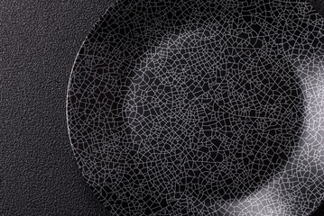 Empty round black plate for food, kitchen utensils on dining table. Empty plate
