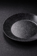 Empty round black plate for food, kitchen utensils on dining table. Empty plate