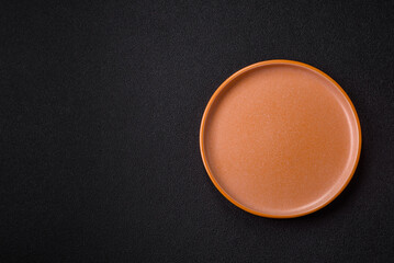 Empty round black plate for food, kitchen utensils on dining table. Empty plate