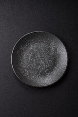 Empty round black plate for food, kitchen utensils on dining table. Empty plate