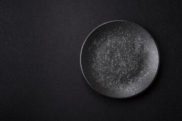 Empty round black plate for food, kitchen utensils on dining table. Empty plate
