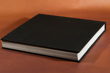 Black Hardcover Book on Brown Surface
