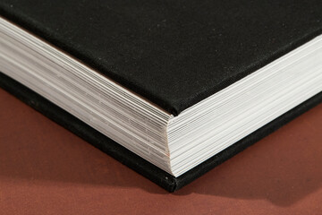 Black Hardcover Book on Brown Surface
