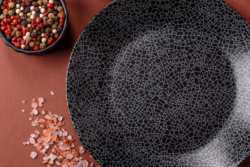 Empty round black plate for food, kitchen utensils on dining table. Empty plate