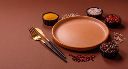 Empty round black plate for food, kitchen utensils on dining table. Empty plate