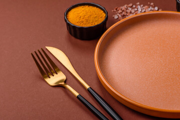 Empty round black plate for food, kitchen utensils on dining table. Empty plate