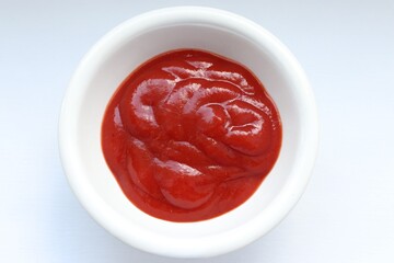 Red tomato ketchup in a minimalist sauce pan - the perfect choice for a modern kitchen, ketchup on a white background close-up