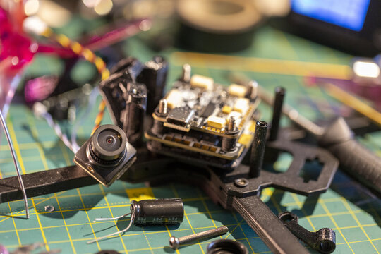 FPV drone components assembly on workbench with green cutting mat background