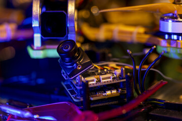 Close-up view of components on vibrant 5 inch FPV drone in workshop setting with neon lighting
